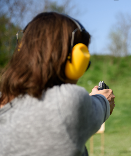 woman shooting in a gun range wearing earmuffs